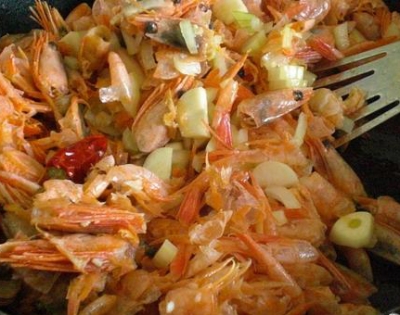 Кладем в сковороду панцири креветок (мясо пока оставляем в сторонке), лук, чеснок, имбирь и перец