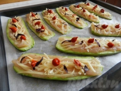 На подготовленные кабачки выложить полоски куриного мяса, присыпать сыром, базиликом, добавить немного соуса