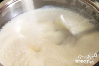 Когда молоко закипит, уменьшить огонь до минимума и тонкой струйкой всыпать манную крупу в кастрюлю, постоянно помешивая